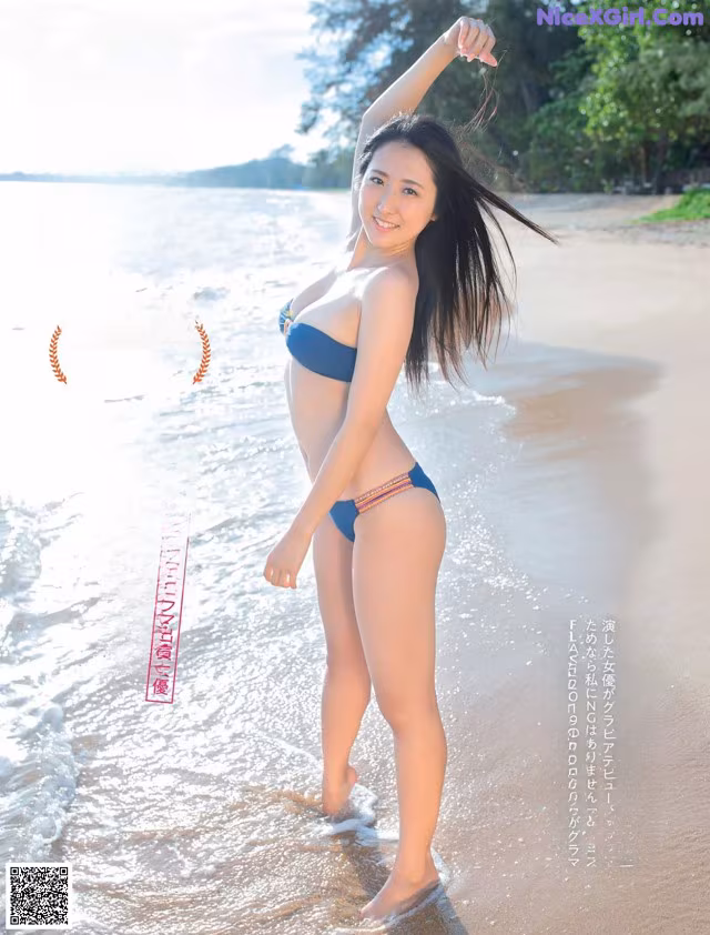 A woman in a blue bikini standing in the water.