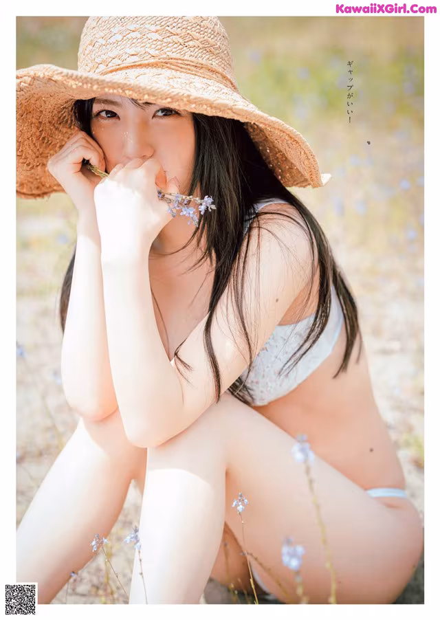 A woman in a straw hat sitting in a field of flowers.