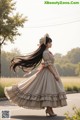 A woman in a long dress is walking down the street.