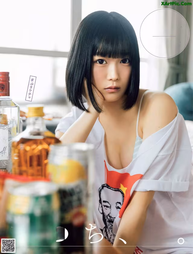 A woman sitting at a table with a bottle of alcohol.