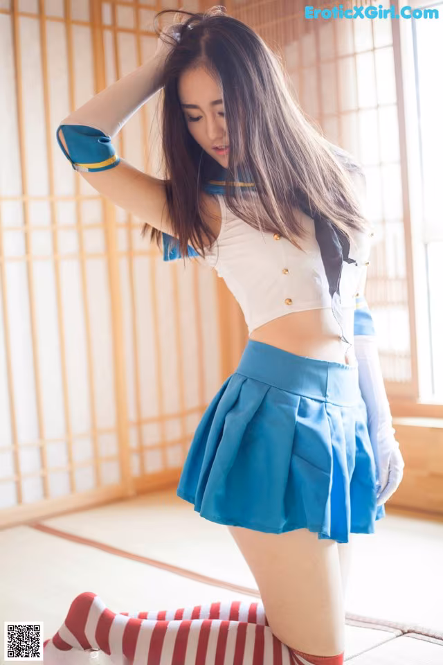 A woman in a blue skirt and white top posing for a picture.