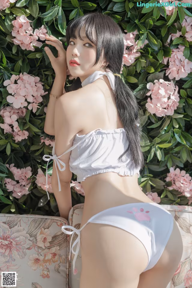A woman in a white bikini sitting on a couch.