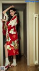 A woman in a red and white kimono standing in a doorway.