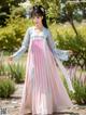 A woman in a pink and blue dress standing in a garden.