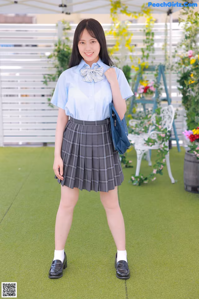 A woman in a blue shirt and plaid skirt posing for a picture.