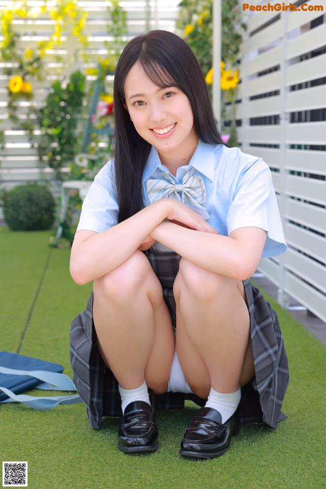 A young woman in a school uniform sitting on the grass.