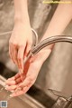 A woman is washing her hands under a faucet.