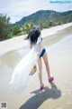 A woman in a white dress is walking on the beach.