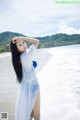 A woman in a white dress standing on a beach.