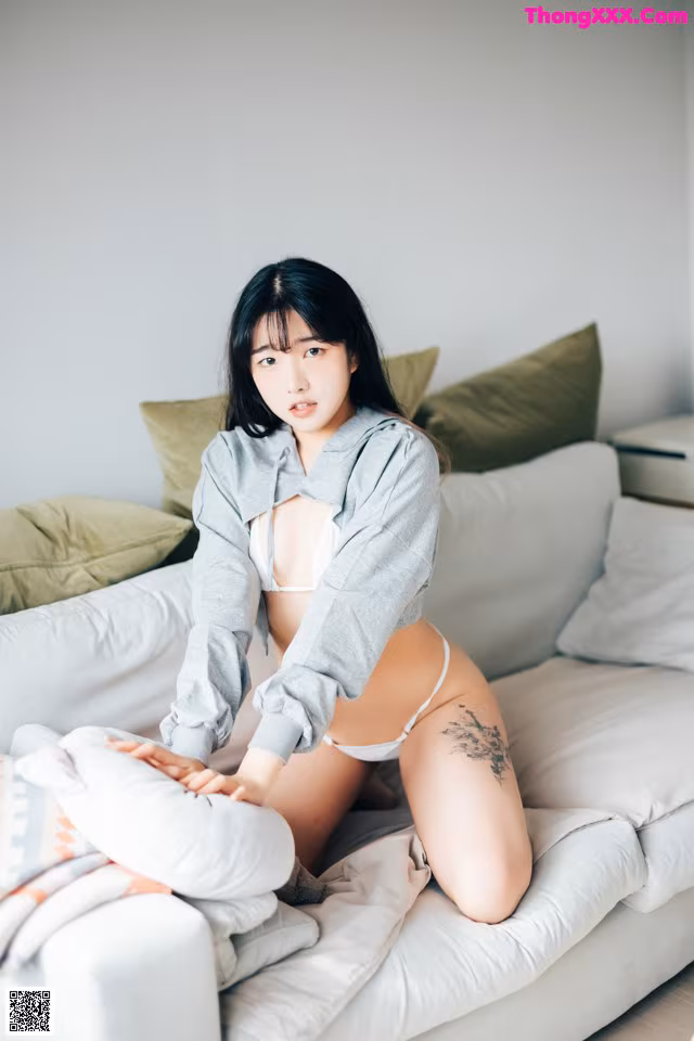 A woman sitting on top of a white couch.