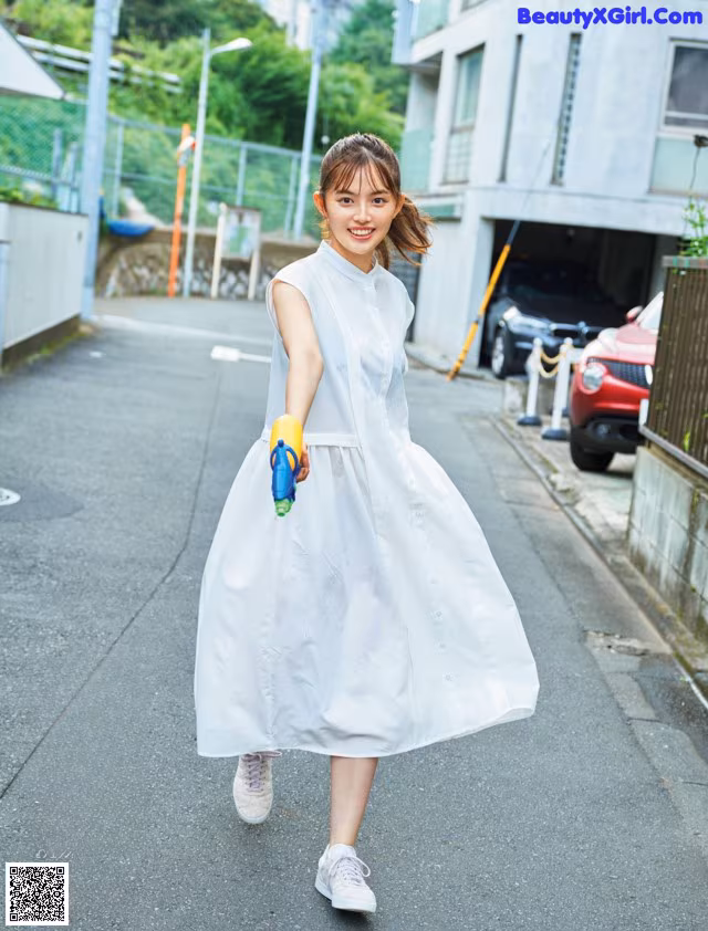 A woman in a white dress is walking down the street.