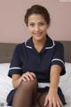 A woman in a blue uniform sitting on a bed.