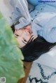 A woman laying on top of a white couch next to a plant.