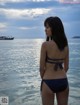 A woman in a blue bikini standing in the water.