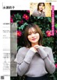 A woman in a gray sweater is posing for a magazine.