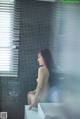 A naked woman sitting on a sink in a bathroom.