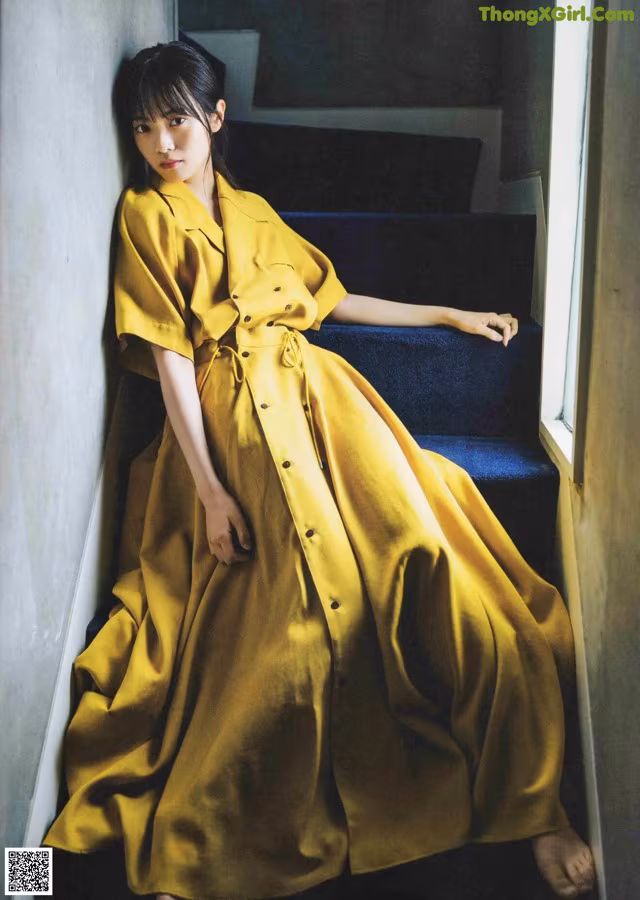 A woman in a yellow dress sitting on the stairs.