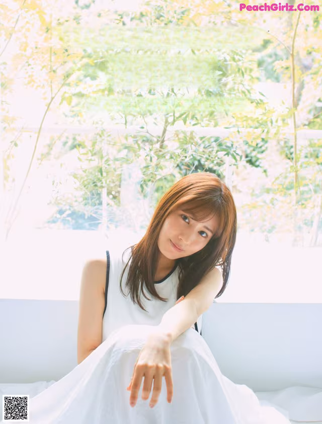 A woman in a white dress sitting on a couch.