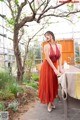 A woman in a red dress standing next to a table.