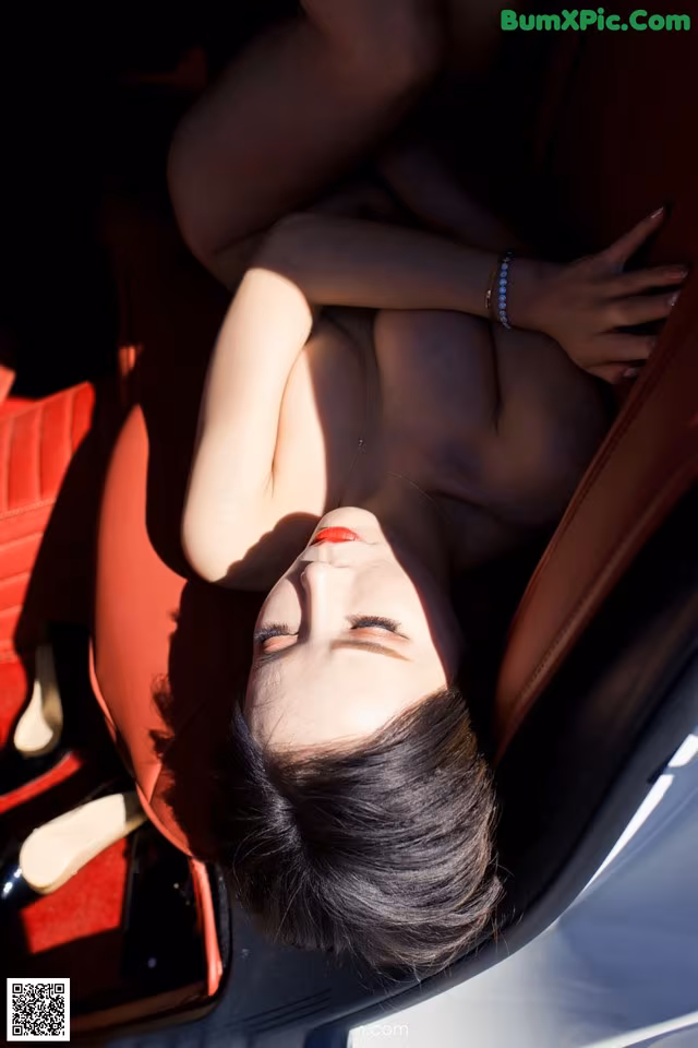 A naked woman laying in the back seat of a car.