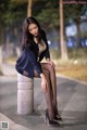 A woman sitting on top of a cement pillar.