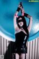 A woman in a black leather outfit holding a pair of handcuffs.