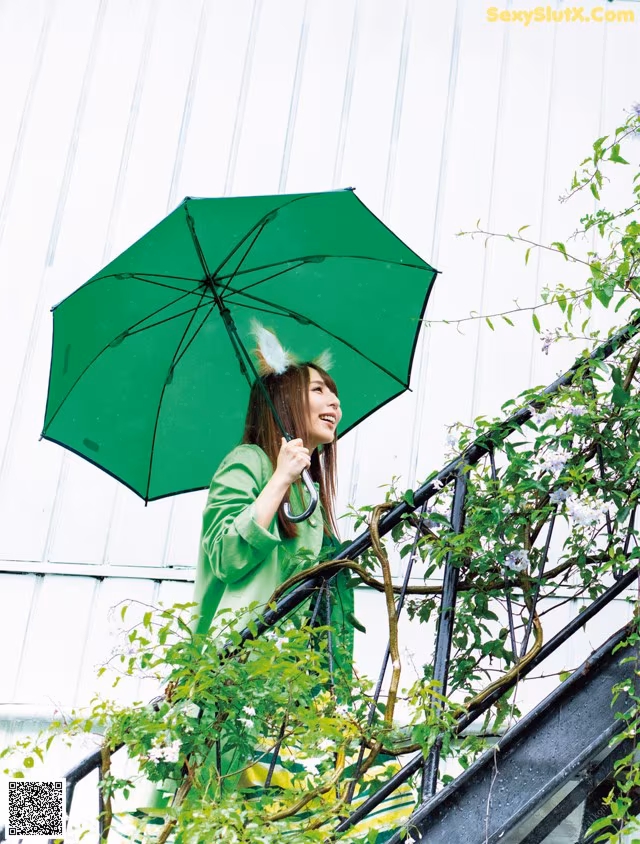 A woman in a green coat holding an umbrella.