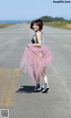 A woman in a pink tutu is walking down the road.