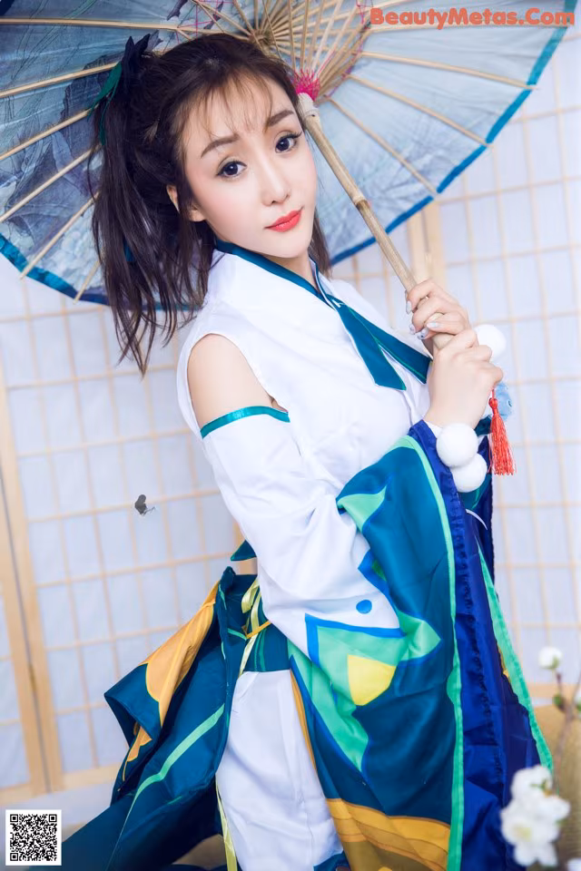 A woman in a blue and green dress holding an umbrella.