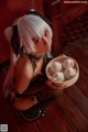 A woman holding a bowl of dumplings on a wooden floor.