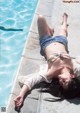 A woman laying on the edge of a swimming pool.