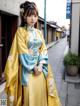 A woman in a yellow and blue hanbok standing on a sidewalk.