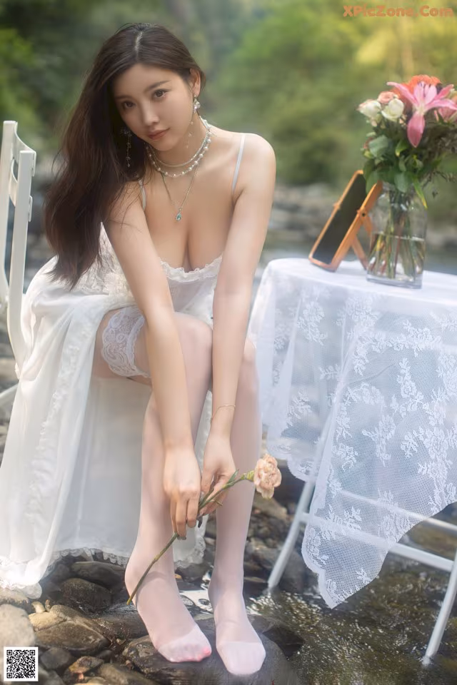 A woman in a white dress sitting on a white chair.