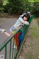 A woman leaning against a fence with an umbrella.