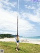 A woman standing next to a pole on a grassy field.