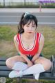 A woman sitting on a bench in a red and white outfit.