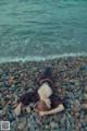 A person laying on a rocky beach next to the ocean.